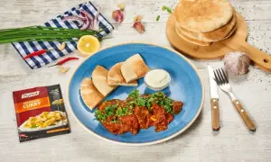 Pyszne wołowina po indyjsku z pitą i dipem. Obok przyprawa curry, czosnek, cytryna i chili.