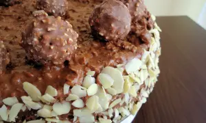 Pyszny tort Ferrero Rocher, obficie udekorowany czekoladowymi kulkami i płatkami migdałów.