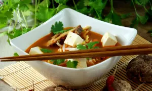 Aksamitna zupa koreańska z kostkami tofu, kiełkami i świeżą kolendrą, gotowa do spożycia pałeczkami.