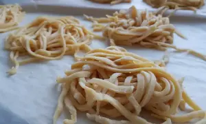 Świeże, domowe tagliatelle uformowane w gniazda. Zastanawiasz się, ile jajek do makaronu? Te wyglądają na idealne!