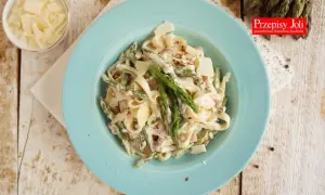 Tagliatelle ze szparagami w kremowym sosie, posypane parmezanem. Pyszne danie na wiosnę.