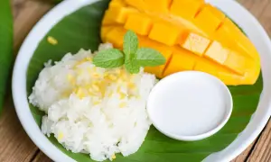 Pyszny mango sticky rice: soczyste mango, kleisty ryż, mleczko kokosowe i listek mięty na liściu bananowca.
