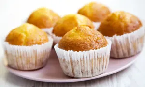 Kilka apetycznych, zdrowe muffinki w papierowych foremkach na różowym talerzu.
