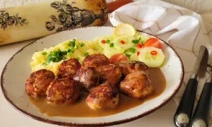 Pyszne pulpety szwedzkie w sosie, podane z puree ziemniaczanym i sałatką z ogórka.