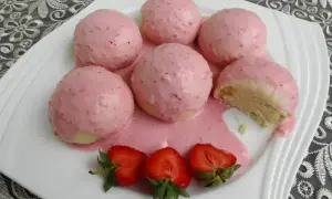 Pyszne parowańce z jagodami, polane kremowym sosem. Na talerzu świeże truskawki.