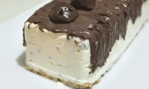 Pyszne lody sernikowe w kształcie bloku, oblane czekoladą z kawałkami czekolady na wierzchu.