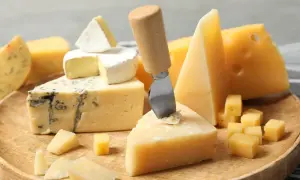 Różnorodne rodzaje serów: pleśniowy, camembert, parmezan i żółte sery, ułożone na drewnianej desce, gotowe do degustacji.