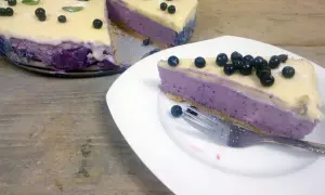 Pyszny sernik jagodowy na zimno z mascarpone, udekorowany świeżymi borówkami i listkami mięty. Idealny deser na letnie dni.