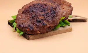 Dwa soczyste kotlety na desce, idealne do burgera. Dowiedz się, jak smażyć burgera, by były tak pyszne!