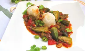 Pyszne okra przepisy na talerzu: duszona okra z pomidorami i ryżem, ozdobione kolendrą i papryczką chili.