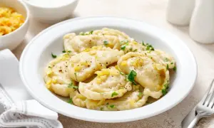 Talerz pysznych, gorących pierogów z cebulką i natką pietruszki. Czy pierogi trzeba od razu gotować? Te wyglądają, jakby właśnie wyszły z garnka!