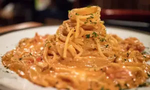 Pyszne spaghetti burrata w kremowym sosie, posypane zieloną pietruszką, czeka na spróbowanie.