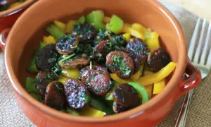Plasterki chorizo w cydrze z papryką i ziołami, podane w glinianej miseczce.