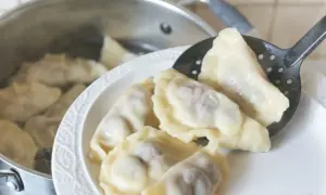 Gorące pierogi wyjmowane łyżką cedzakową z garnka. Czy pierogi przelewa się zimną wodą? Nie, gorące prosto z wody na talerz.