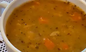 Gęsta, aromatyczna grochówka wege z kawałkami marchewki i przyprawami w białej miseczce.