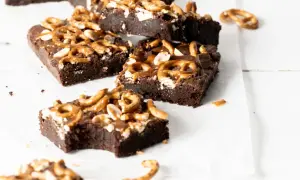 Czekoladowe brownie z karmelem i orzechami, posypane kawałkami precelków. Pyszna przekąska.