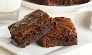Dwa wilgotne brownie z nutellą, posypane solą morską, na białym talerzyku.