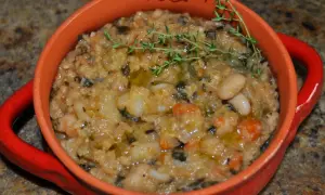 Gęsta, sycąca zupa ribollita z fasolą, warzywami i ziołami, podana w pomarańczowej miseczce.