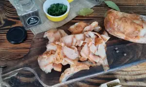 Pokrojone, przyprawione mięso na kebaba leży na drewnianej desce obok przypraw i ziół.