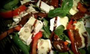Pyszna sałatka z camembertem i suszonymi pomidorami, polana sosem balsamicznym i posypana słonecznikiem. Idealna na lekki posiłek.