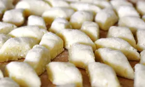 Świeżo przygotowane kopytka z cynamonem, posypane mąką, czekają na ugotowanie.