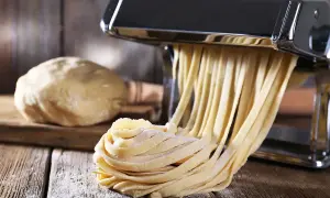 Maszyna do makaronu tworzy świeże tagliatelle z ciasta. Idealny sposób, jak zrobić makaron w domu.