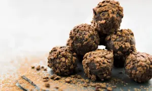 Stos pysznych, czekoladowych kulek Ferrero Rocher, posypanych kakao, kusi swoim wyglądem.