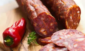 Kawałki pikantnego chorizo, czerwona papryczka i natka pietruszki na desce. To właśnie chorizo, co to za przysmak!