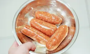 Cztery surowe kiełbaski chorizo w folii spożywczej, gotowe do przygotowania pysznego dania.
