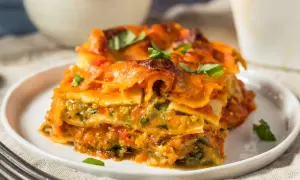 Pyszna lasagne wegetariańska z warzywami i sosem pomidorowym, udekorowana świeżą bazylią.