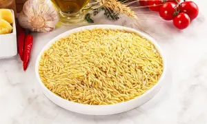 Miseczka pełna drobnego makaronu orzo, obok czosnek, papryczki chili, pomidorki i oliwa.