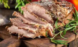 Pokrojony, pieczony boczek z ziołami na desce. Idealny przykład, jak zapeklować boczek do pieczenia, by był soczysty i aromatyczny.