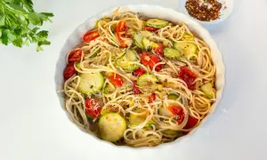 Pyszny makaron z cukinią, pomidorkami i parmezanem, posypany płatkami chili.