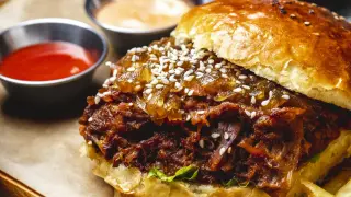 Sloppy Joe w bułce z sezamem, podany z ketchupem i sosem. Pyszne danie, które zachwyci każdego.