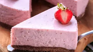 Pyszne ptasie mleczko truskawkowe na kruchym spodzie, udekorowane świeżą połówką truskawki.