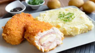 Chrupiący kotlet szwajcarski z rozpływającym się serem i szynką, podany z kremowym purée ziemniaczanym.