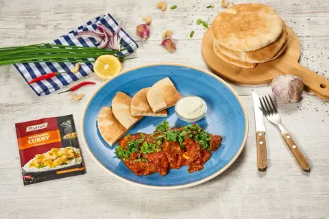 Pyszne wołowina po indyjsku z pitą i dipem. Obok przyprawa curry, czosnek, cytryna i chili.
