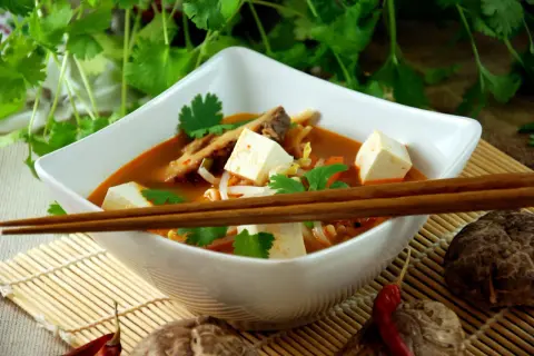 Aksamitna zupa koreańska z kostkami tofu, kiełkami i świeżą kolendrą, gotowa do spożycia pałeczkami.