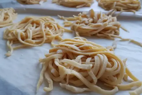 Świeże, domowe tagliatelle uformowane w gniazda. Zastanawiasz się, ile jajek do makaronu? Te wyglądają na idealne!