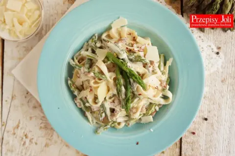 Tagliatelle ze szparagami w kremowym sosie, posypane parmezanem. Pyszne danie na wiosnę.