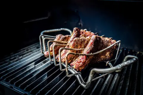 Żeberka w stojaku na grillu, gotowe na prawdziwy barbecue po polsku. Soczyste mięso pieczone na ruszcie.