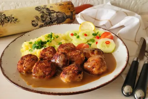 Pyszne pulpety szwedzkie w sosie, podane z puree ziemniaczanym i sałatką z ogórka.