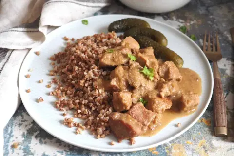 Pyszny gulasz z szynki podany z kaszą gryczaną i ogórkami kiszonymi. Aromatyczne danie, które zachwyci każdego smakosza.