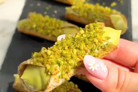 Chrupiące rurki wypełnione kremowym nadzieniem, obficie posypane zielonymi, aromatycznymi pistacjami. Te cannoli pistacjowe wyglądają niezwykle apetycznie.