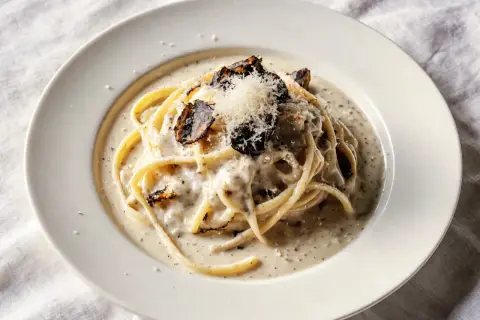 Pyszny makaron z truflami w kremowym sosie, posypany parmezanem i kawałkami czarnej trufli.