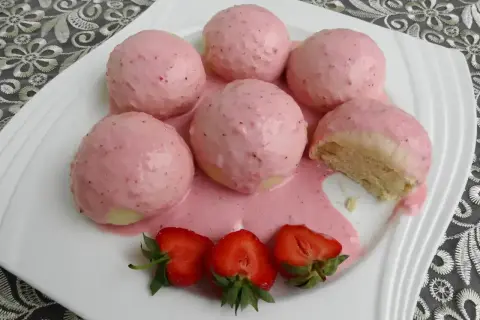 Pyszne parowańce z jagodami, polane kremowym sosem. Na talerzu świeże truskawki.