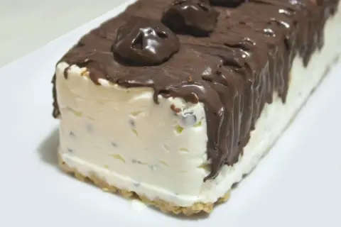 Pyszne lody sernikowe w kształcie bloku, oblane czekoladą z kawałkami czekolady na wierzchu.