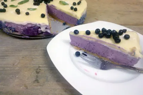 Pyszny sernik jagodowy na zimno z mascarpone, udekorowany świeżymi borówkami i listkami mięty. Idealny deser na letnie dni.