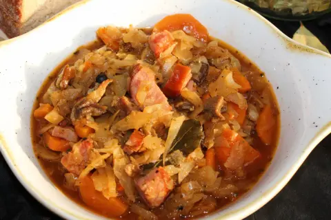 Bigos ze słodkiej kapusty Ani gotuje się powoli, by wydobyć głębię smaku. Widać kawałki kiełbasy, marchewki i liście laurowe.