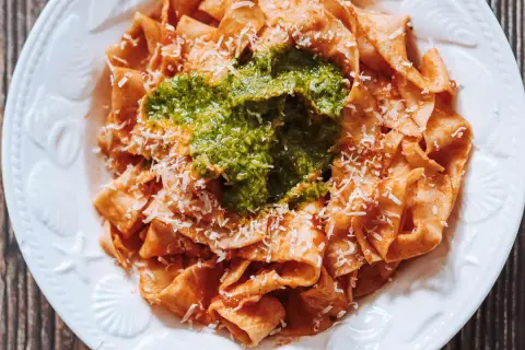 Pappardelle all'arrabbiata przepis: szeroki makaron z pikantnym sosem pomidorowym, zielonym pesto i parmezanem.